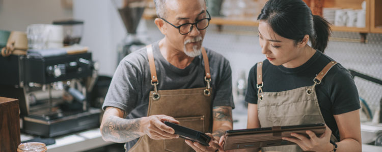 senior man owner and daughter using digital tablet at counter