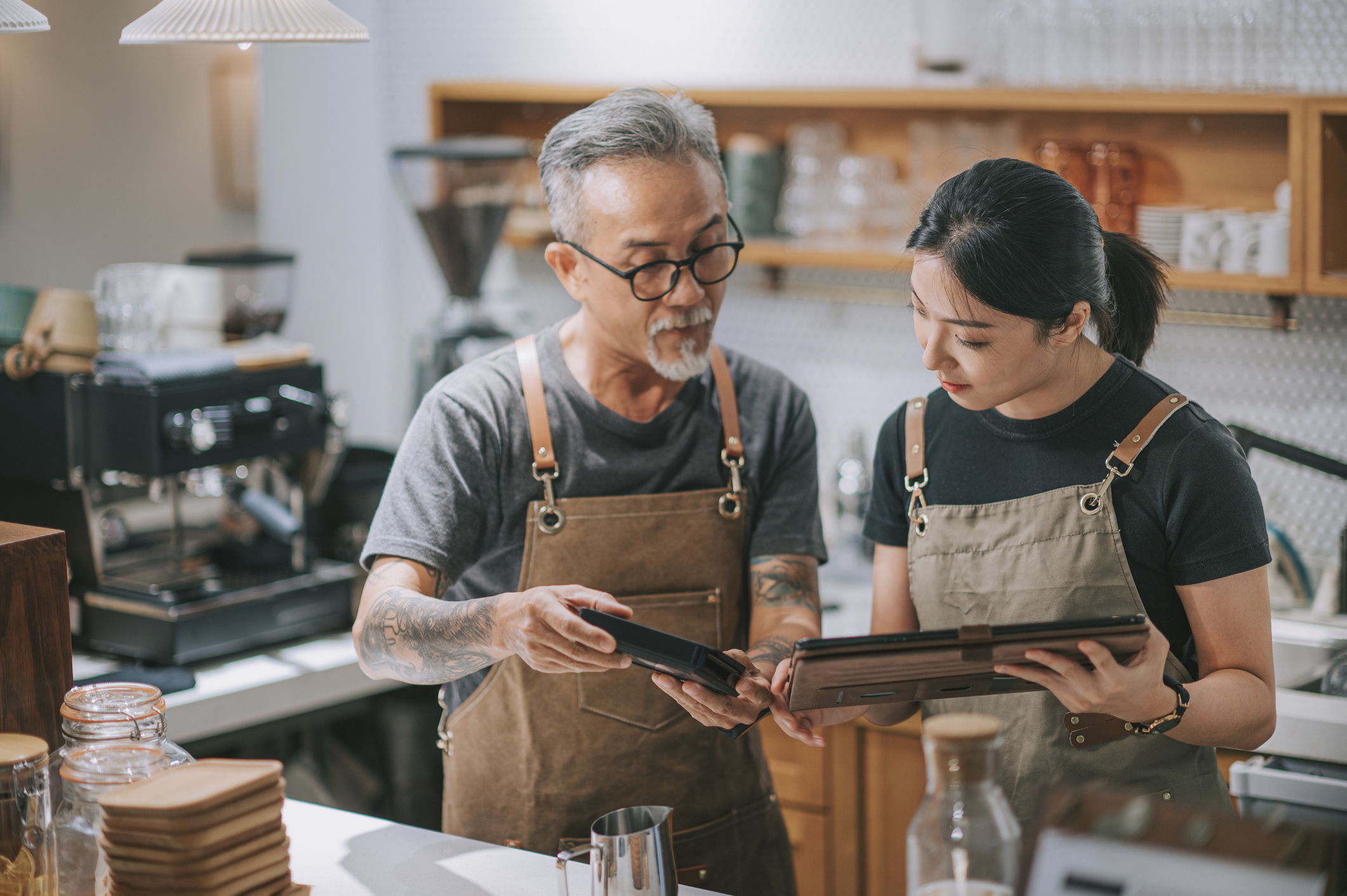 senior man owner and daughter using digital tablet at counter